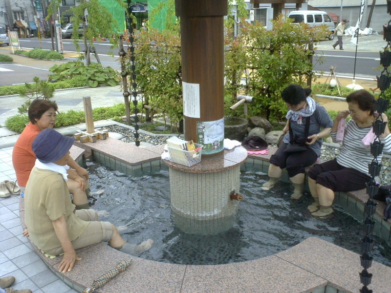 A cluster of ladies enjoy a foot onsen near the train station.
